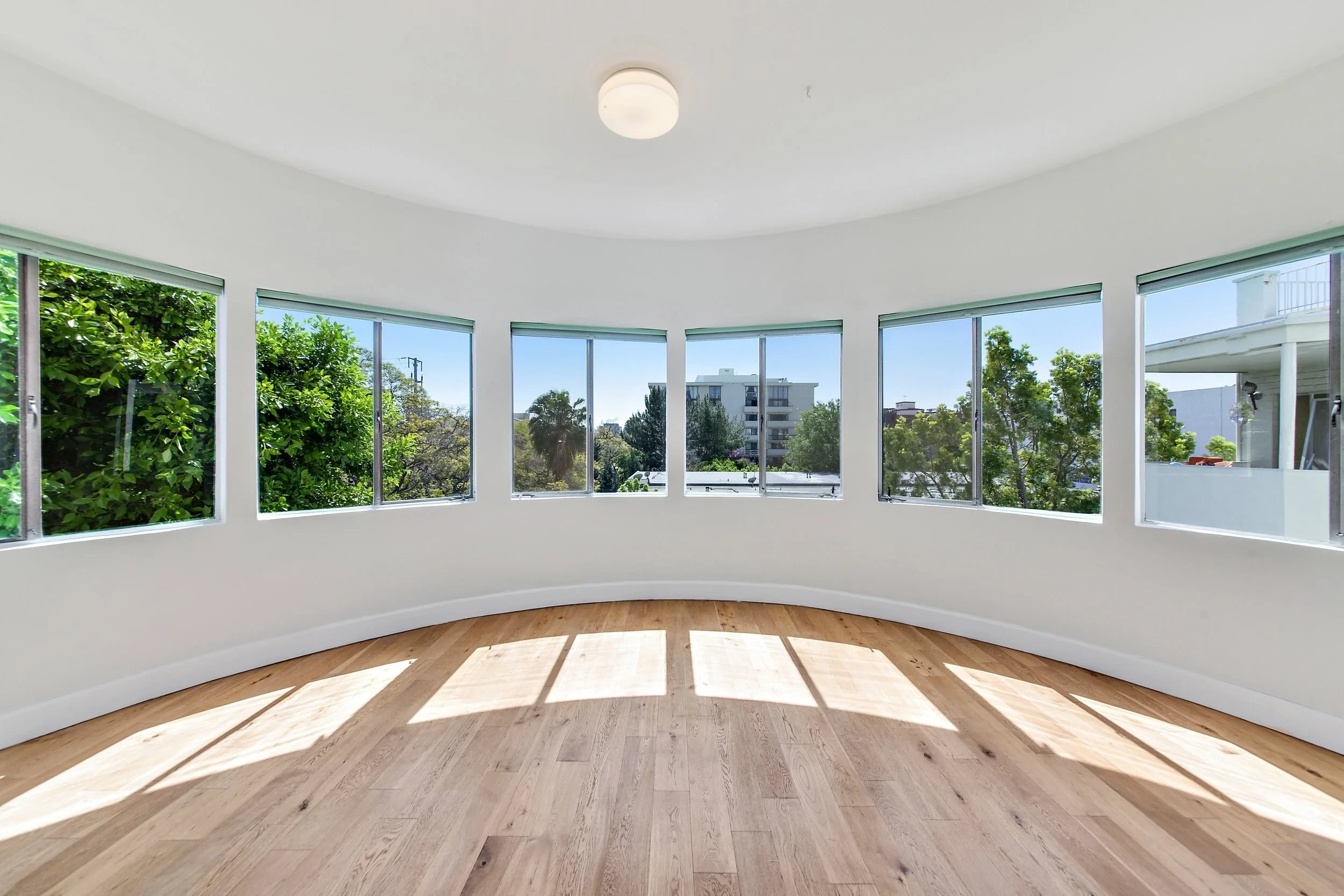 Sunlit room with curved panoramic windows and hardwood floors