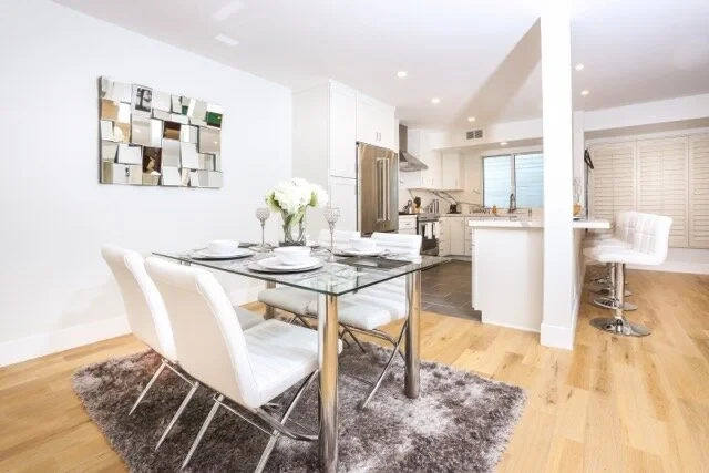 Dining area with glass table, white chairs and open kitchen