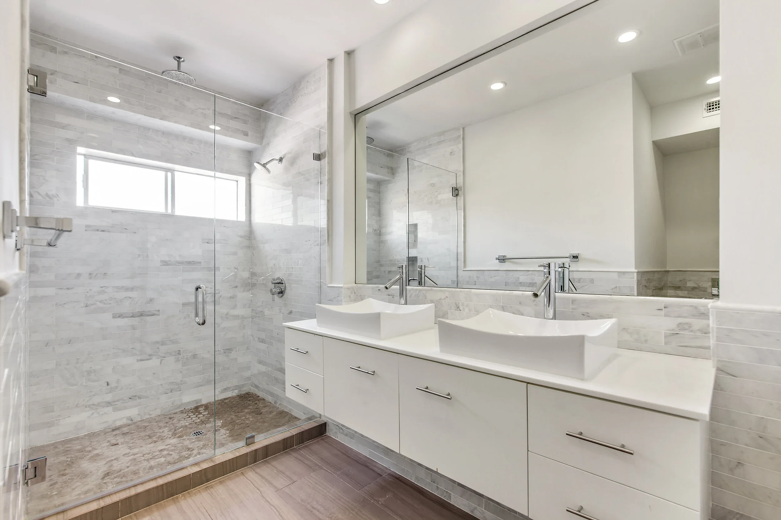 Spa bathroom with double vessel sinks, marble tile and glass shower