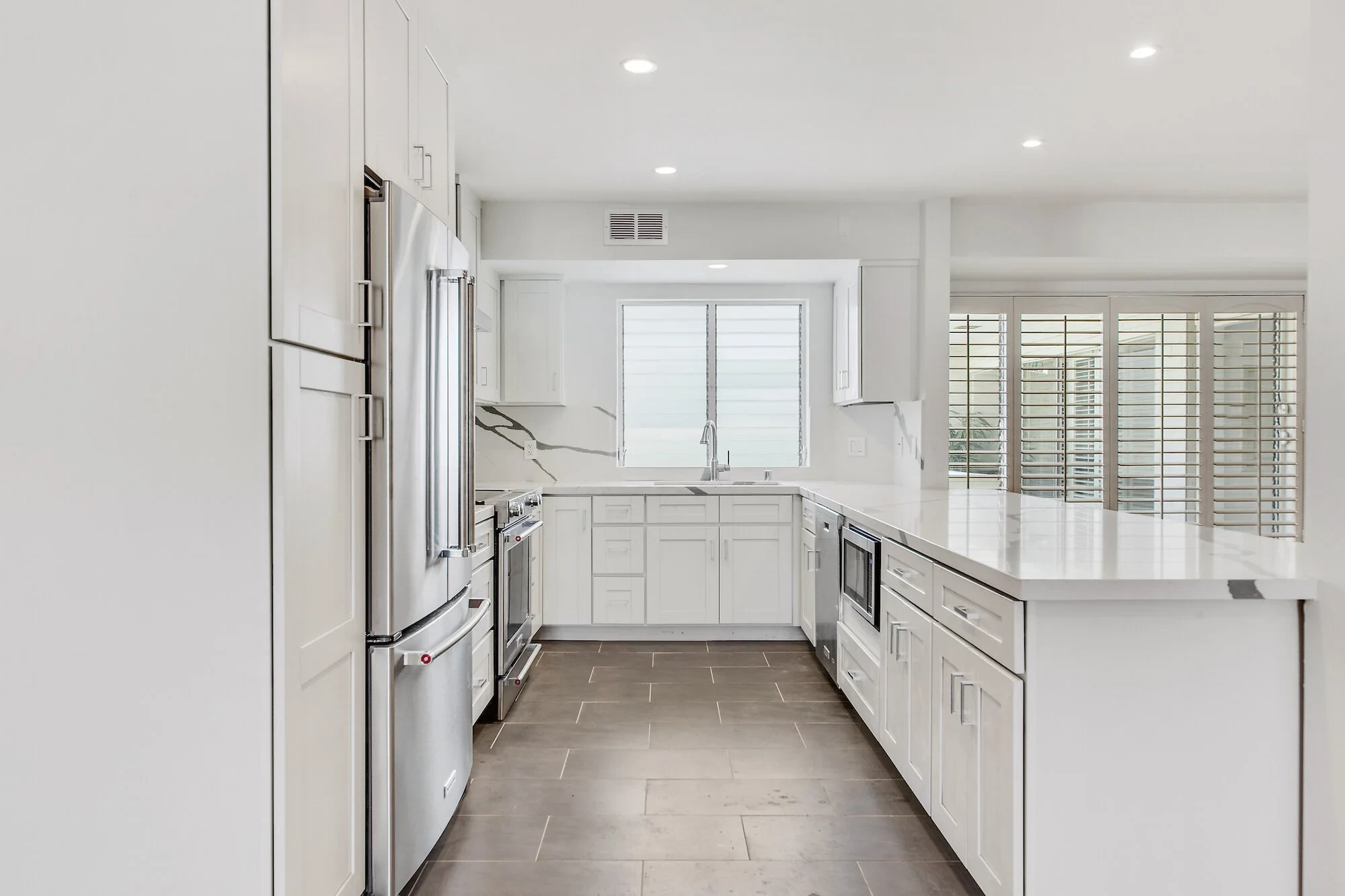 Luxury kitchen with white cabinetry, quartz counters and stainless appliances