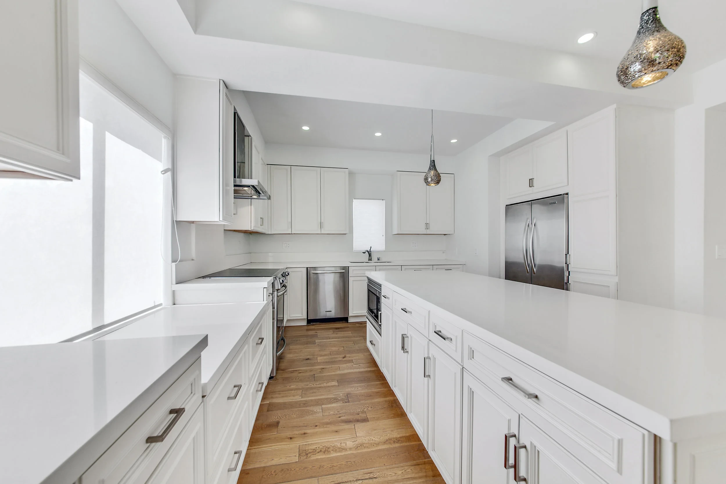 Chef's galley kitchen with white cabinetry, quartz counters and stainless appliances