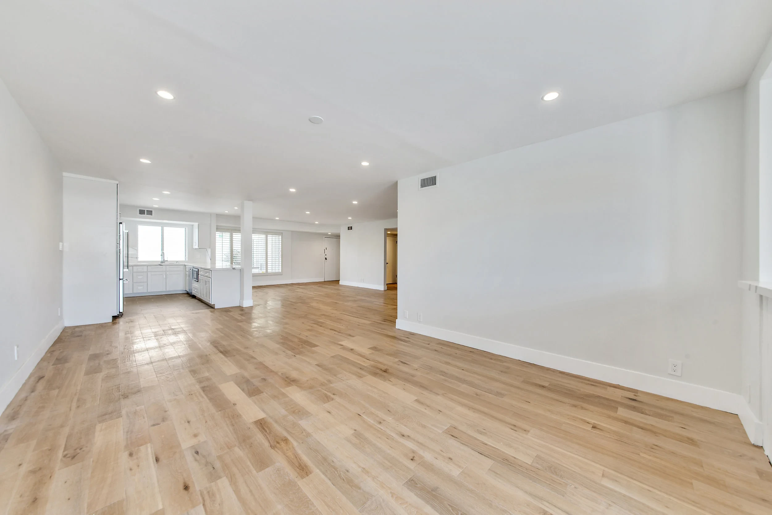Expansive open-plan living area with hardwood floors and recessed lighting