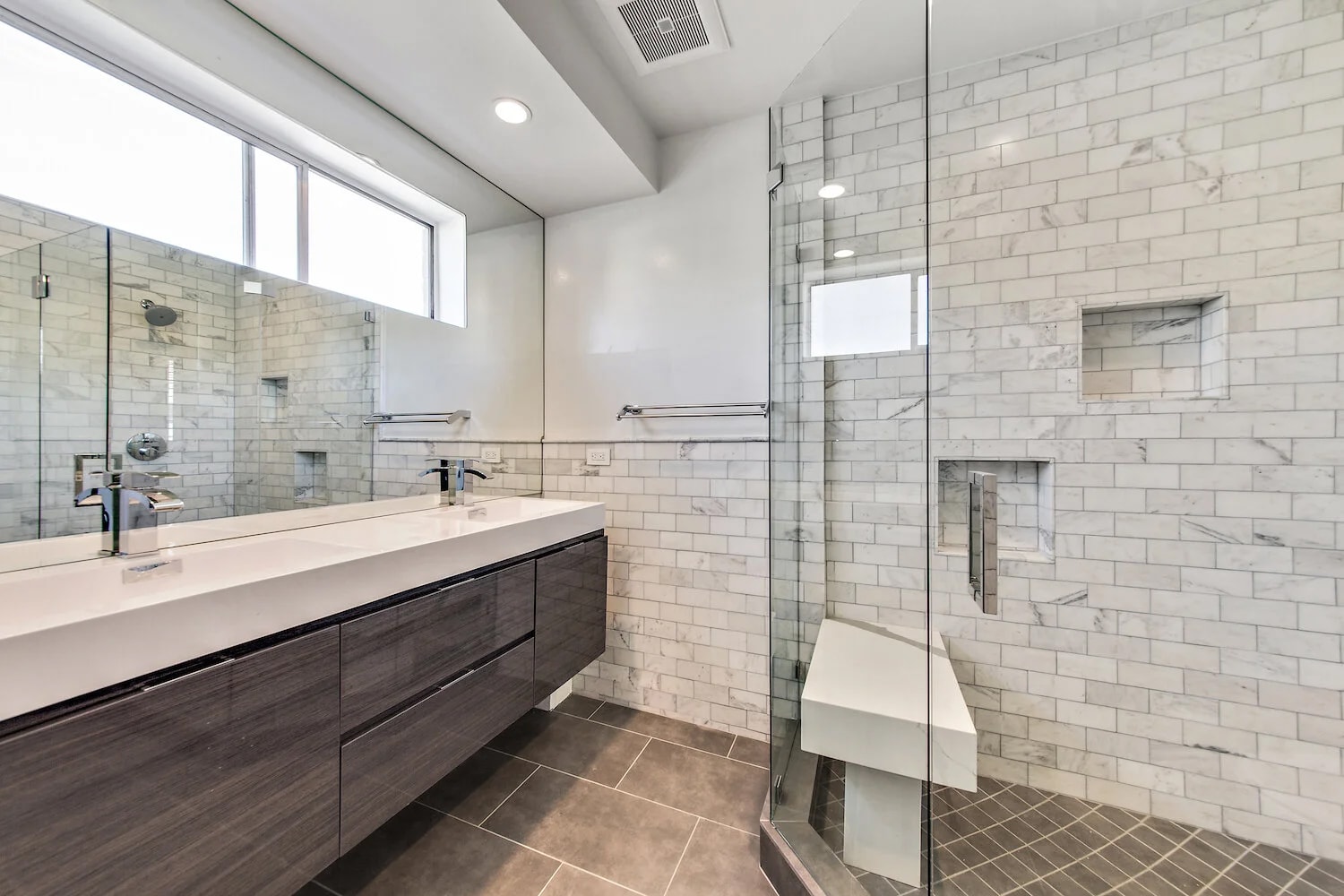 Luxury bathroom with marble subway tile and glass shower enclosure