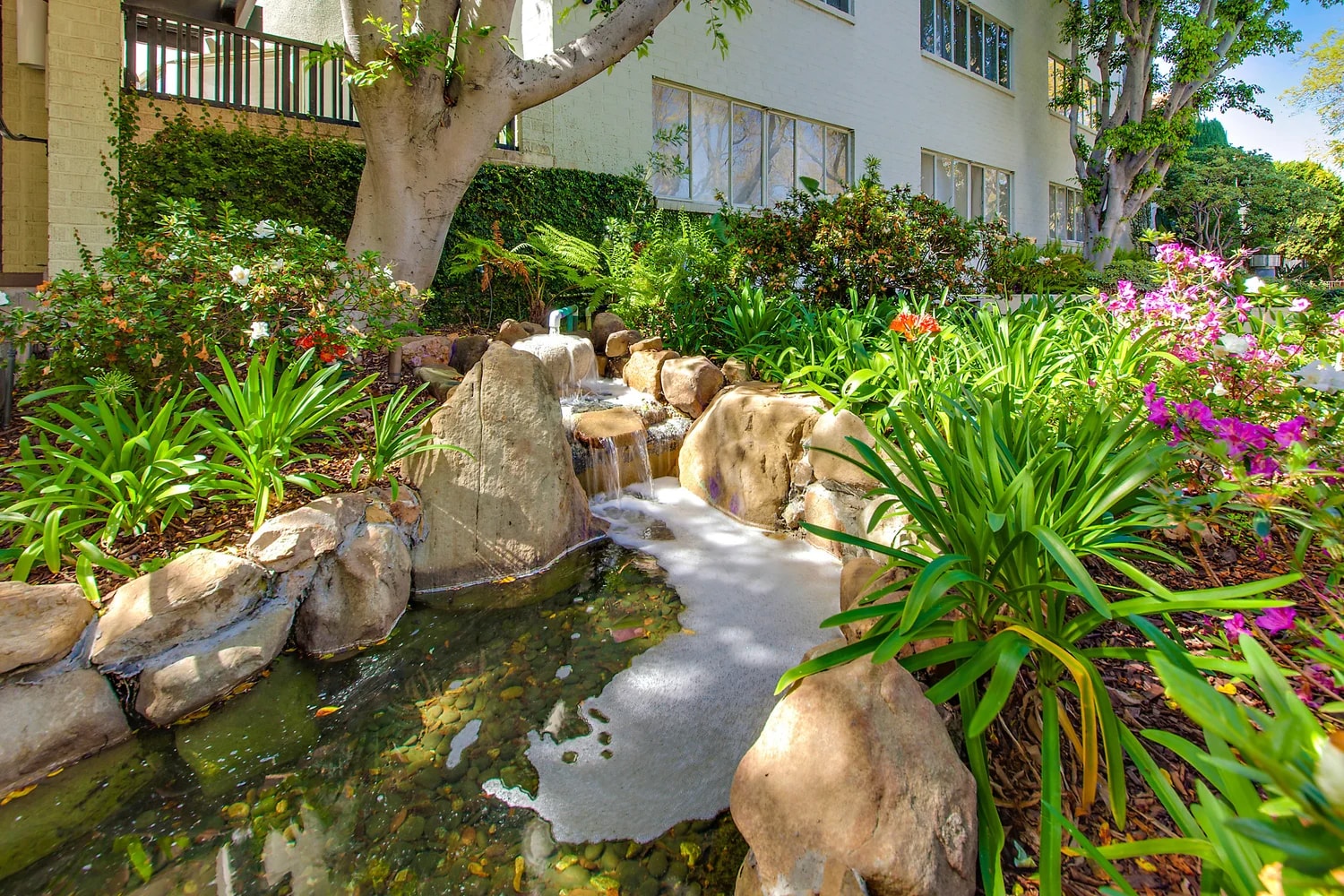 Lush garden courtyard with waterfall feature and tropical plants